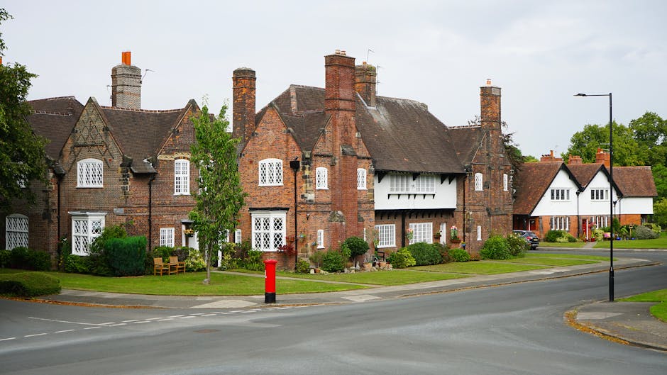 An aerial black-and-white photograph of a residential neighborhood showing a variety of detached and semi-detached houses with pitched roofs, surrounded by trees and gardens. The streets are winding a